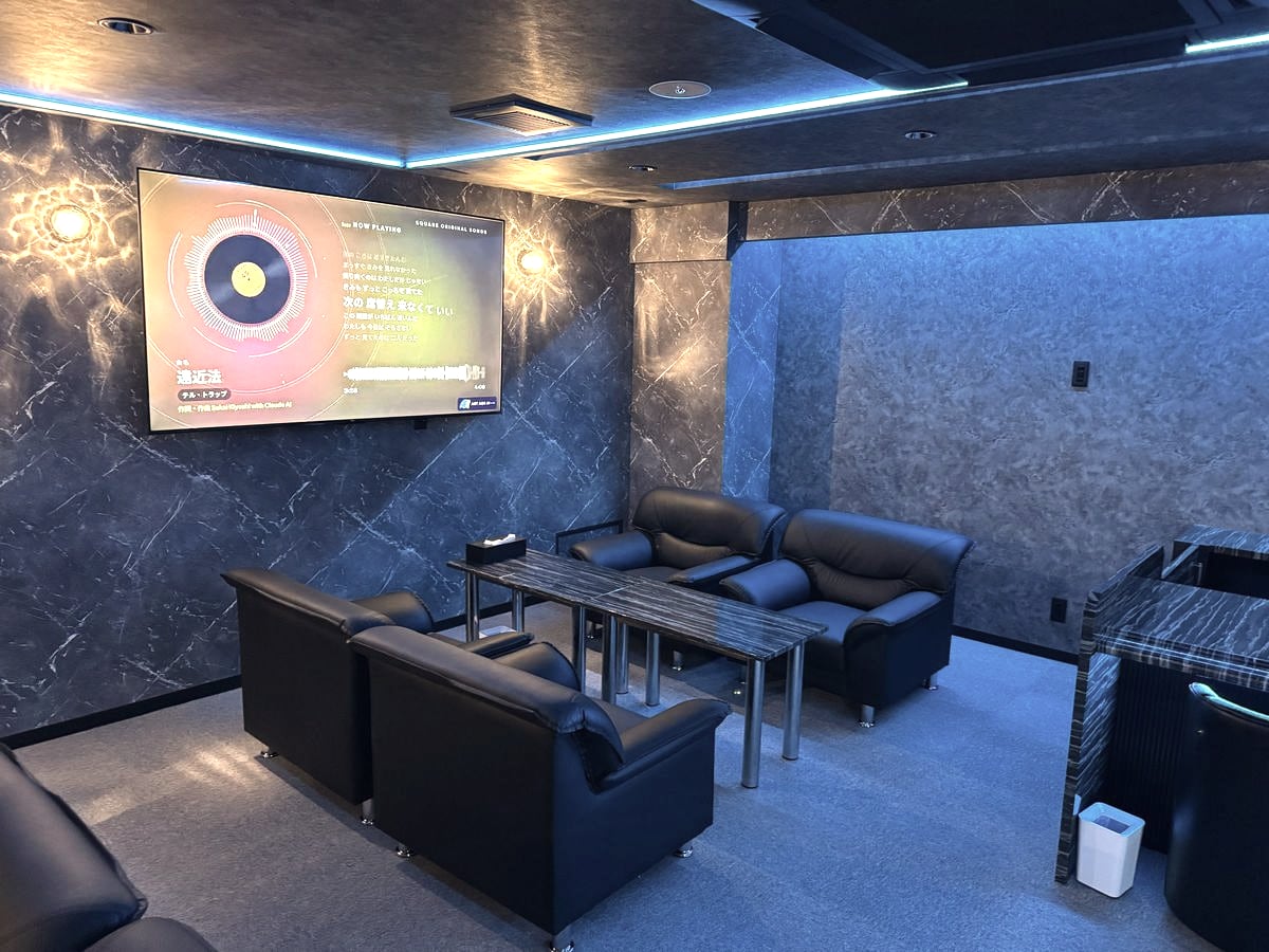 天井の青い間接照明の下、黒いソファがテーブルを囲む SQUARE の店内